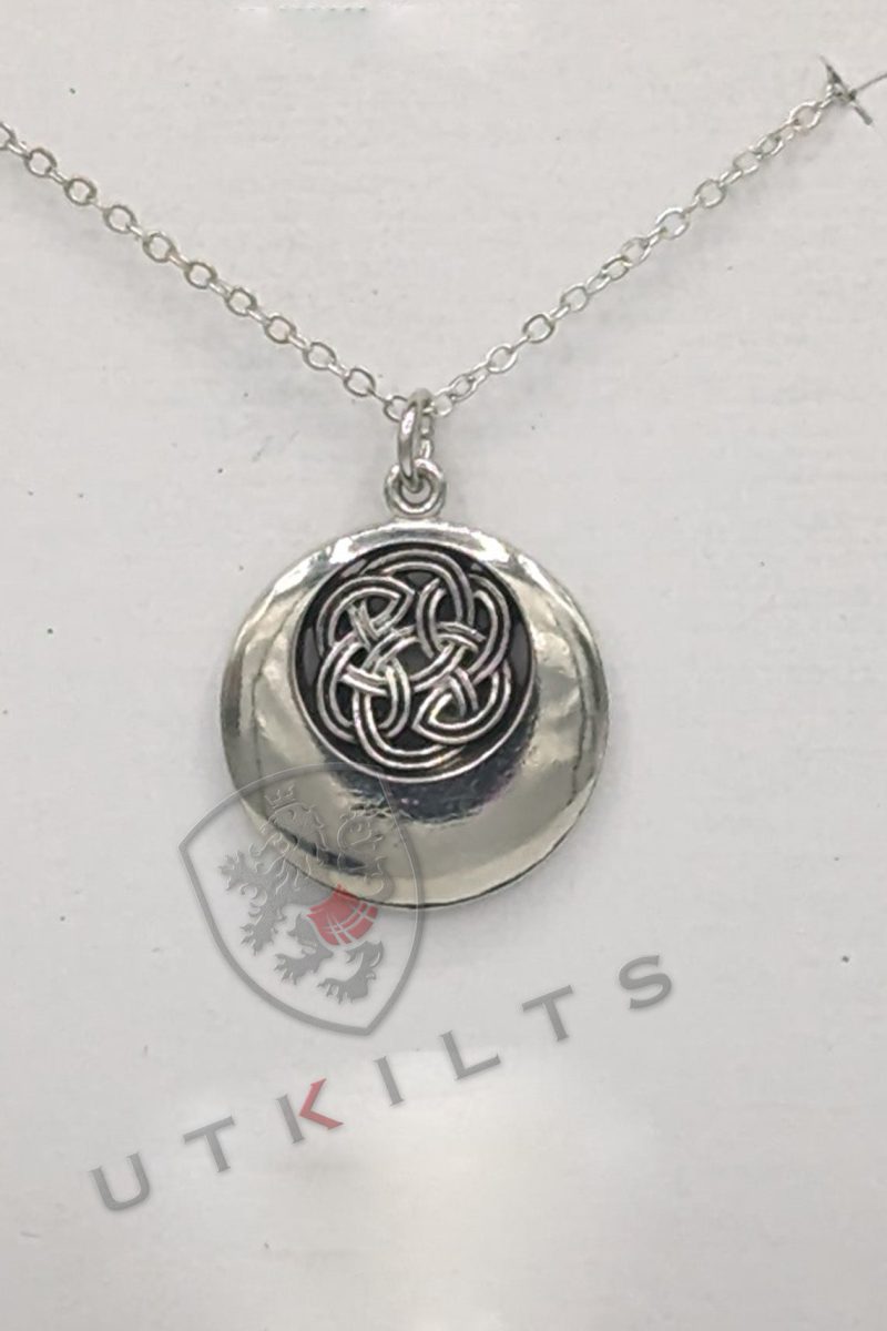 A silver pendant featuring an intricate black and white Celtic design, showcasing a rounded knot pattern.