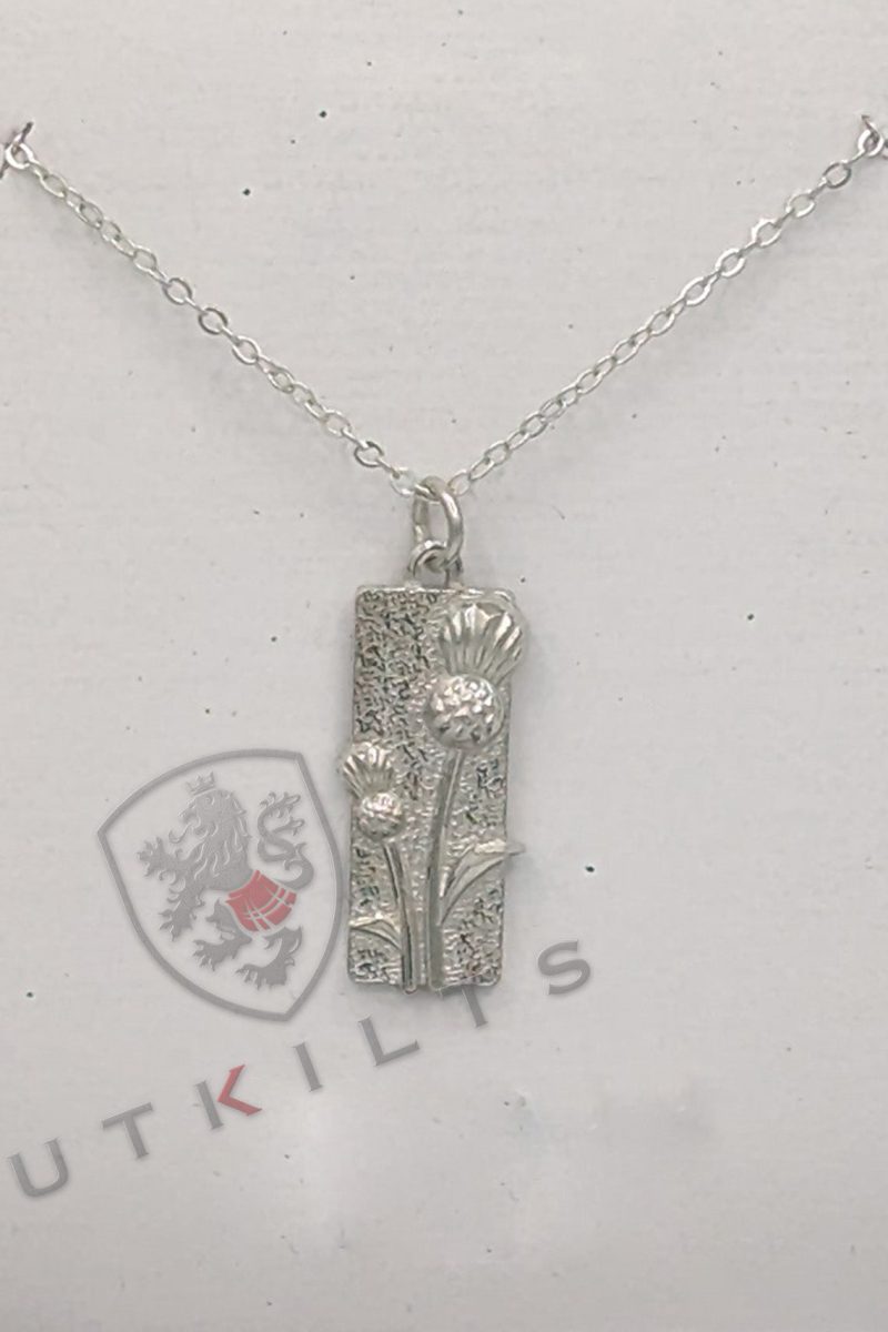 A silver necklace adorned with a rectangular pendant, complemented by a thistle design.